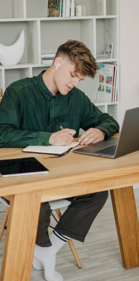 Guy writing on a notebook with AirPod on